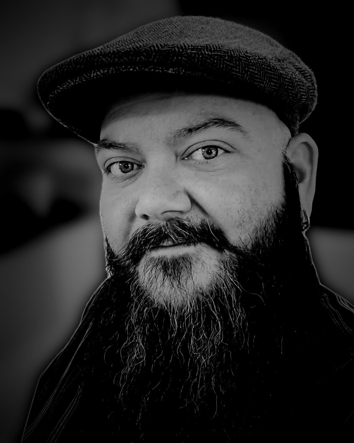Jonathan Burton, a bearded man in a herringbone flat cap, looking at the camera.